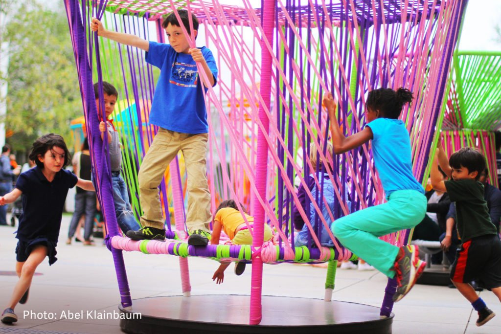 Children play on Los Trompos, a structure based on 'spinning tops' and made for woven colorful textiles.