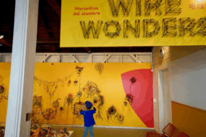 A young boy displays his artwork on a gallery wall at a children’s creativity museum