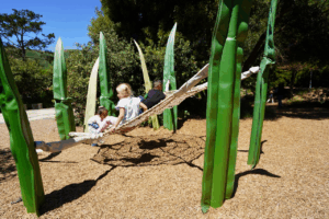 Children engaging in play-based learning on a giant spider web at the Bay Area Discovery Museum