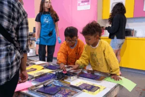 Two young boys create art in the print shop of a children’s creativity museum