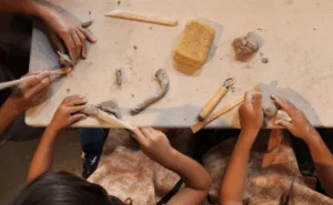 A bird’s eye view of children’s hands sculpting clay, one of the best art activities for kids