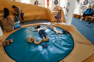 Kids play on a squishy water bed with stuffed animals at a children’s creativity museum
