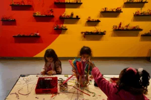 Three young girls engage in play-based learning with arts and crafts at the Bay Area Discovery Museum