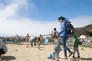 Parents play with their young children at BADM beach with sand toys