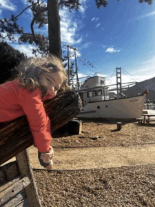 A young girl poses for Bay Area Discovery Museum photos with “Faith,” an old fishing boat in the background